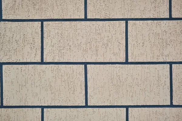 Büyük tuğlalardan oluşan duvar griye boyanmış.