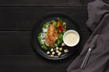  Sezar salatası ve chiken, siyah ahşap bir masada, üst manzara, insan yok.,