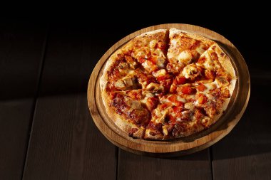  pizza on a wooden board, with BBQ chicken, mozzarella, roasted garlic and marinara sauce, on a brown blackground, 