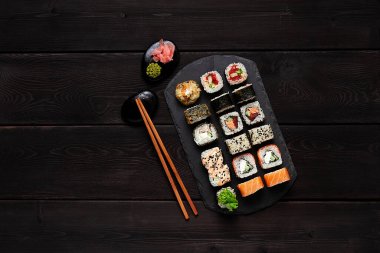 Japon seti, roll philadelphia klasiği, somon teriyaki, baharatlı somon, yasai maki, siyah tabakta, üst manzara, yatay, insan yok., 