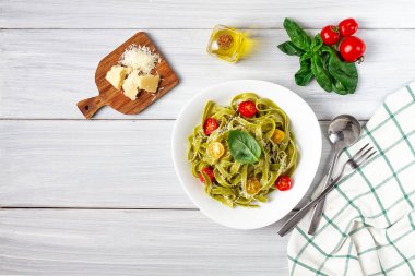 Ispanaklı, kiraz domatesli ve peynirli yeşil makarna, beyaz bir masada, yatay, insan yok.,