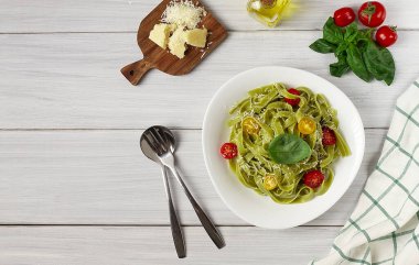 Ispanaklı, kiraz domatesli ve peynirli yeşil makarna, beyaz bir masada, yatay, insan yok.,