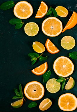 Arka plan, dilimlenmiş kireç ve limon, nane aromalı narenciye, koyu yeşil bir masada, üst manzara, insan yok.,