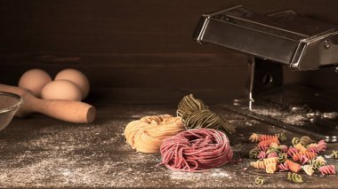 Tagliolini makarnası çiğ, çok renkli, İtalyan yemeği ahşap bir masada, kırsal tarzda, yatay, insan yok.,