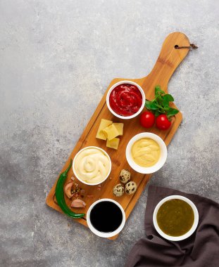 Set, soslar, ketçap, mayonez, peynir, soya, yeşil, kesme tahtasının üzerinde, malzemelerle, gri bir masada, üst manzara, insan yok.,