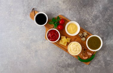 Set, soslar, ketçap, mayonez, peynir, soya, yeşil, kesme tahtasının üzerinde, malzemelerle, gri bir masada, üst manzara, insan yok.,