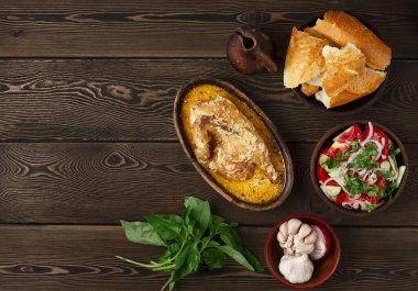 Geleneksel Gürcü yemeği, Chkmeruli, kremalı sarımsak soslu tavuk, kil tavada ketsi, ahşap masada, insan yok.,