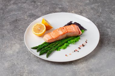 Kızarmış somon balığı, kuşkonmaz ve limon, beyaz bir tabakta, yatay olarak.,