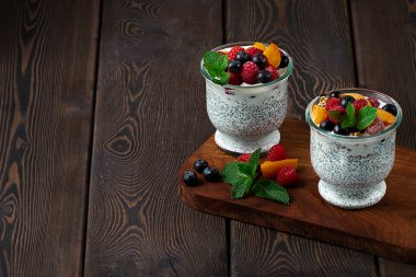 Puding, Chia tohumları ve böğürtlenli, bardaklarda, tahtadan bir masada sağlıklı kahvaltı, yatay, insan yok.,