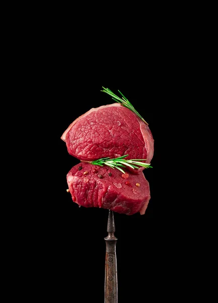 Beef steak, raw, with spices, on a fork, concept, rustic, black background, vertical, no people, — Stock Photo, Image