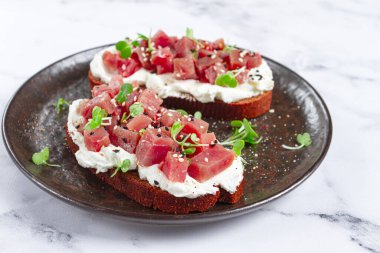 Sandviç, krem peynirli çavdar ekmeği, otlu ton balığı filetosu, siyah tabakta kahvaltı, ev yapımı.,