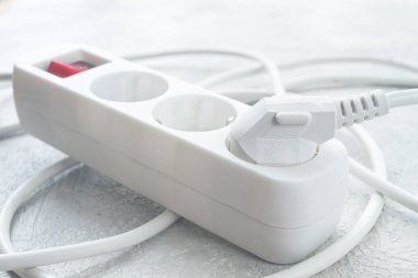 Çoklu prizli güç şeridi ve gündüz vakti dokulu bir yüzeyde dağınık bir ayarda bir anahtar.