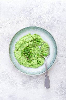 Canlı yeşil bezelye püresi taze bezelye ve mikroyeşilliklerle kaplı sığ bir kaseyi doldurur. Yemek taze ve davetkar görünüyor. Hafif ve besleyici bir yemek için her zaman ideal..