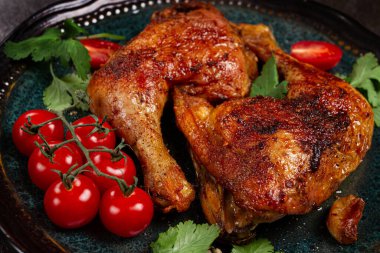 Kızarmış tavuk bacağı, taze kiraz domatesleri ve otlarla servis edilmiş, tabakta, ev yapımı, insan yok.,