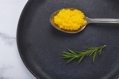 İnci yuzu, yuzu havyarı. Koyu gri bir tabakta, kaşığın üstünde inci. Hiç insan yok..