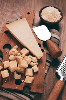 Taze dilimlenmiş ve rendelenmiş peynir, parmesan peyniri, büyük anne hazzı. Grana padano. Ahşap kesim tahtasının üzerinde, köylü tarzı, insan yok.