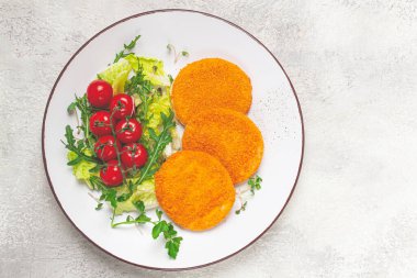 Kızarmış balık pirzolası, balık köftesi, beyaz bir tabakta, taze marul yaprakları, roka ve kiraz domatesleri, ev yapımı, insan yok.,