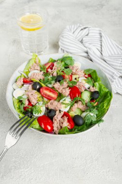 salad with canned tuna, vegetable salad with quail eggs, lettuce and romaine leaves, red onion, cherry tomatoes, olives, keto food, healthy eating,