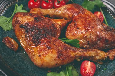 Kızarmış tavuk bacağı, taze kiraz domatesleri ve otlarla servis edilmiş, tabakta, ev yapımı, insan yok.,