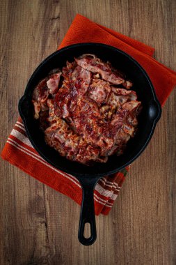 Kavrulmuş domuz pastırması, dökme demir tavada, ahşap bir masada, kırsal tarzda, insan yok.