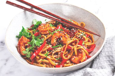 udon eriştesi, sebzeli ve taze otlu karides, çubuklu bir kâse, hafif arka plan, ev yapımı, insan yok.,