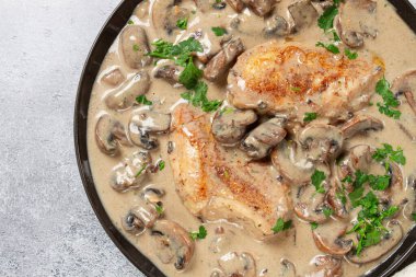 Mantarlı krema soslu tavuk, siyah tabakta, insan yok.