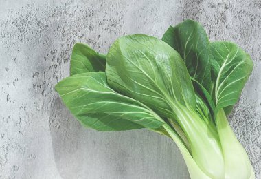 Taze bok choy, açık gri bir yüzeye serilmiş, üst manzara, doğal ışık.,