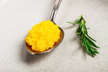 Yuzu havyarı incedir, kaşık üzerinde, üst görünüm, arka plan aydınlık, insan yok..