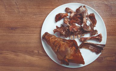 Kızarmış domuz kafası, kemik ve et kalıntıları, beyaz bir tabakta, insan yok, yakın plan.,