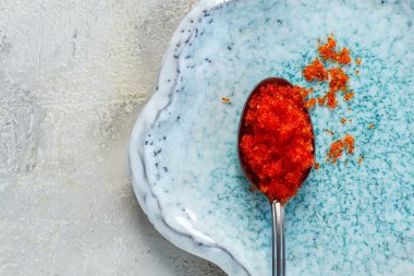 Turuncu uçan balık havyarlı bir kaşık, Tobiko, açık mavi bir tabakta, havyar rulo ve suşi için, yakın plan.,