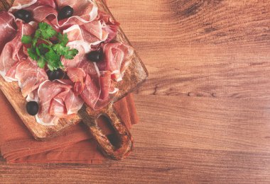 Kesme tahtasında dilimlenmiş jambon, zeytin ve otlarla, atıştırmalık, kahvaltı, insan yok.,