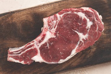 Çiğ biftek, kovboy bifteği, tahta doğrama tahtası, mermer masa, üst manzara, insan yok.,