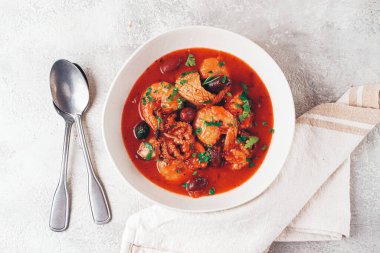 Domates soslu deniz ürünleri, beyaz tabakta zeytin.,