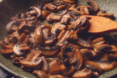 Kızarmış mantarlar tavada, ahşap çatalla, ev yapımı, insan yok.,