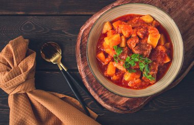 Patatesli, domates soslu, baharatlı ve otlu, yakın plan, insan yok, siyah arka planda.