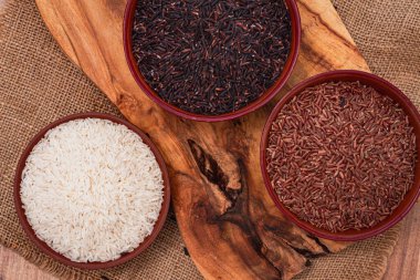 Kırmızı, siyah ve beyaz pirinç seti, bir kâse içinde, ahşap bir yüzey üzerinde, kırsal tarzda, üst manzara