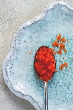 Turuncu uçan balık havyarlı bir kaşık, Tobiko, açık mavi bir tabakta, havyar rulo ve suşi için, yakın plan.,