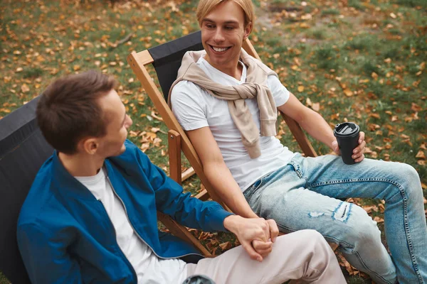 爱同性恋夫妇一起坐在户外 手牵手喝咖啡 两个帅哥在公园里谈恋爱Lgbt概念 — 图库照片