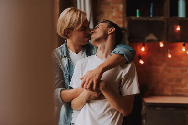 Evdeki sevecen eşcinsel çift. Mutfakta sarılıp öpüşen iki yakışıklı adam. LGBT kavramı.