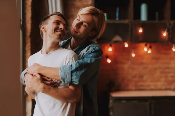 Evdeki sevecen eşcinsel çift. Mutfakta sarılıp öpüşen iki yakışıklı adam. LGBT kavramı.