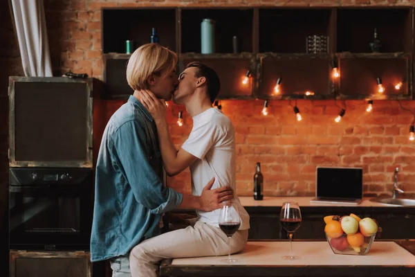 Evdeki sevecen eşcinsel çift. Mutfakta sarılıp öpüşen iki yakışıklı adam. LGBT kavramı.