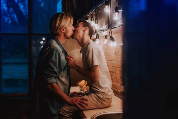 Evdeki sevecen eşcinsel çift. Mutfakta sarılıp öpüşen iki yakışıklı adam. LGBT kavramı.