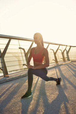 Çekici kız güneş doğarken spor yapıyor ve poz veriyor. Şehirde spor haberleri. Şehir konseptinde sağlıklı yaşam tarzı. Sabahları koşuyorum. Koşmaya hazırlanılıyor.