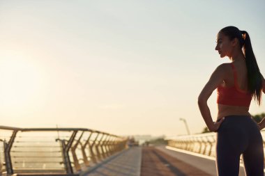 Güzel kız gün doğumunda spor yapıyor ve poz veriyor. Genç bir kadının bakış açısı. Şehirde spor haberleri. Şehir konseptinde sağlıklı yaşam tarzı. Sabahları koşuyorum.
