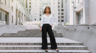 Şehirde genç ve çekici bir iş kadını. Bilgisayarla modern iş merkezinin yanında yürüyorum..