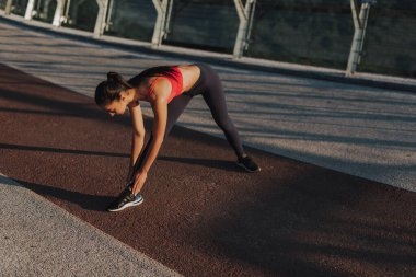 Çekici kız güneş doğarken spor yapıyor ve poz veriyor. Şehirde spor haberleri. Şehir konseptinde sağlıklı yaşam tarzı. Sabahları koşuyorum. Koşmaya hazırlanılıyor.