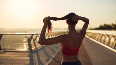 Güzel kız gün doğumunda spor yapıyor ve poz veriyor. Genç bir kadının bakış açısı. Şehirde spor haberleri. Şehir konseptinde sağlıklı yaşam tarzı. Sabahları koşuyorum.