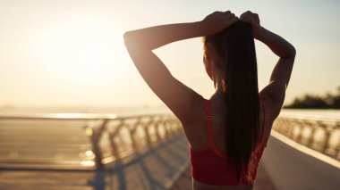 Güzel kız gün doğumunda spor yapıyor ve poz veriyor. Genç bir kadının bakış açısı. Şehirde spor haberleri. Şehir konseptinde sağlıklı yaşam tarzı. Sabahları koşuyorum.