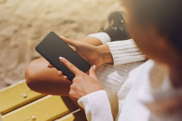 Kendime ayıracak vaktim var. Güzel genç bir kadın dışarıda tek başına vakit geçiriyor. Güneşli bir günde elinde akıllı bir telefonla bankta oturan bir kızın kesilmiş görüntüsü.