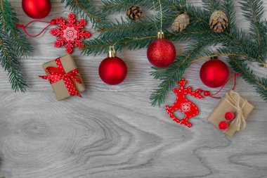  Köknar dalları, kırmızı ve altın toplar, tahta kar taneleri, geyik ve el sanatları kağıdındaki hediyelerden oluşan gri bir panoda yeni yıl modeli. Metin için alanı olan düz alan